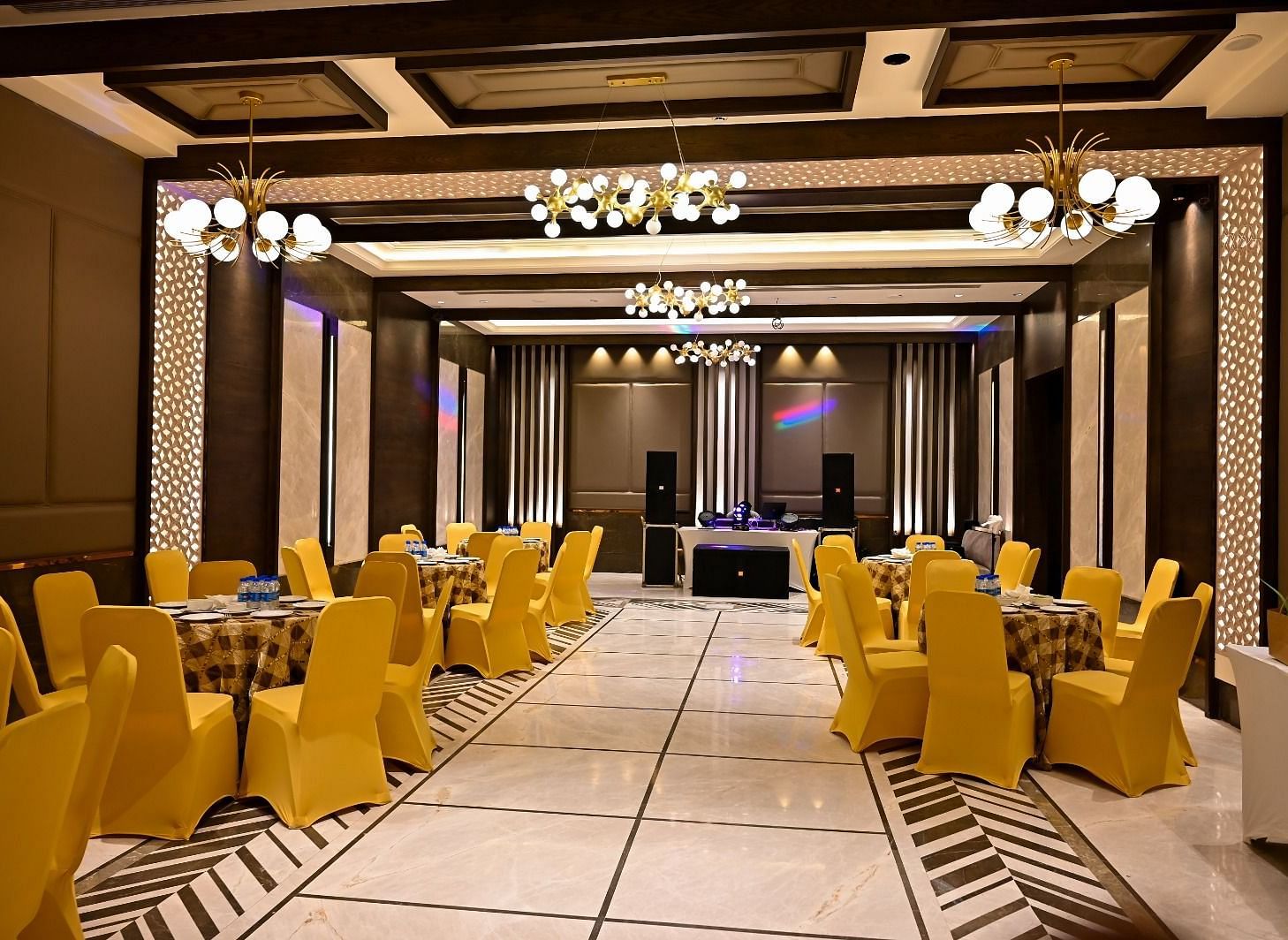 Event space with round tables and chairs arranged, featuring fancy lights hanging from the ceiling at BluSalzz Residence, Amritsar